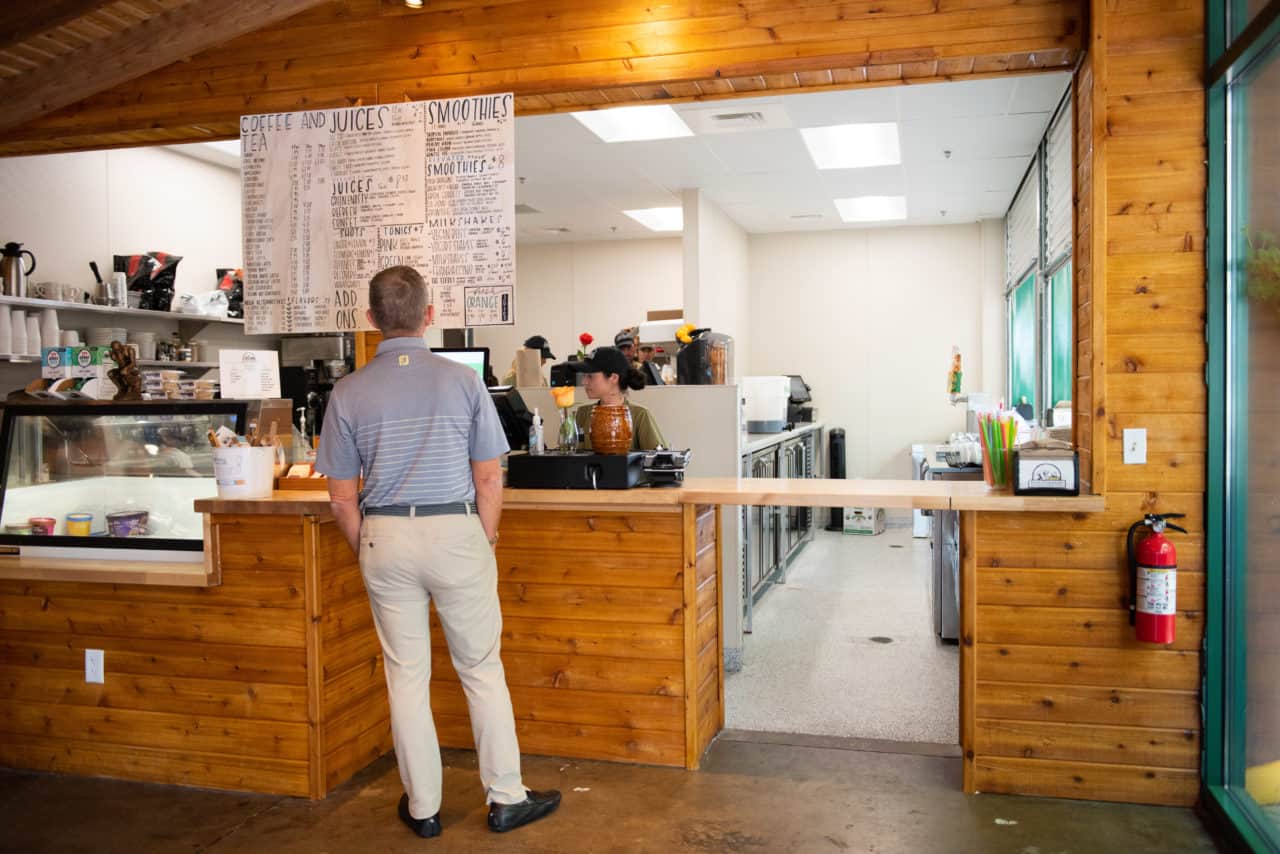 Juice bar A man in a collared shirt and slacks ordering a drink from the hand drawn menu at the organic juice bar